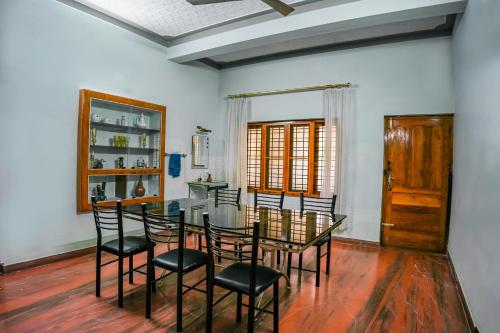 a dining room with a glass table and chairs at Athira Homestay in Kollengode