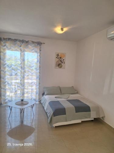 a bedroom with a bed and a table next to a window at The Golden Island apartments in Krk