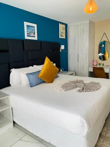 a bedroom with a large white bed with a blue wall at Solovina Guest House in Foso