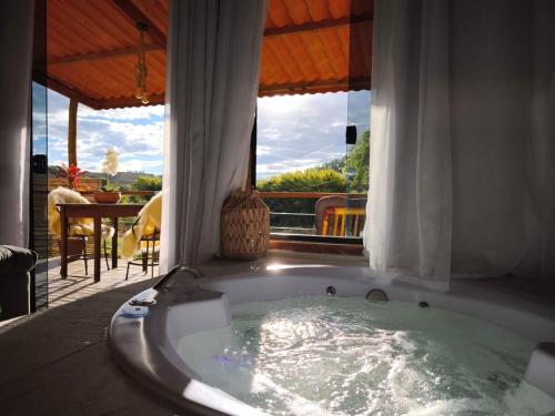 a jacuzzi tub in a room with a patio at Vale Infinito Chalé in Córrego do Bom Jesus
