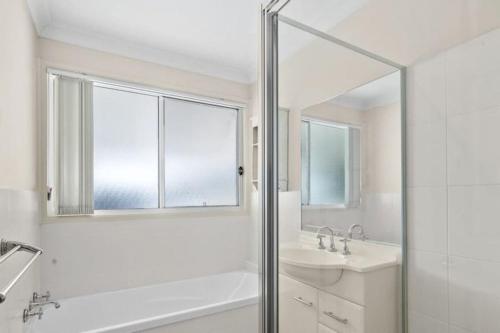 a white bathroom with a shower and a sink at Serena Shores Holiday Escape in St Georges Basin
