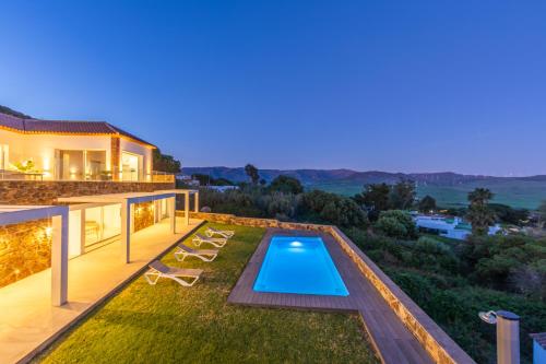 a backyard with a swimming pool and a house at Villa Las Palmeras Valdevaqueros Suites, Pool & Sea Views in Tarifa