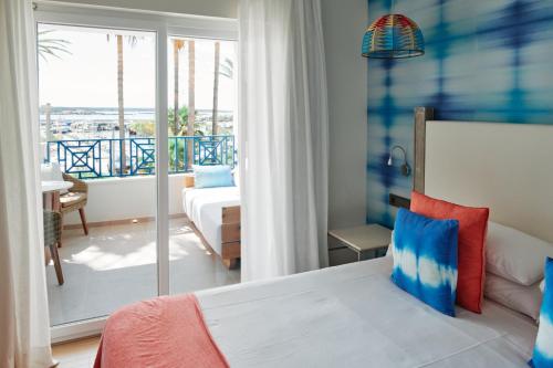 a bedroom with a bed and a view of the ocean at Hotel Honucai in Colònia de Sant Jordi