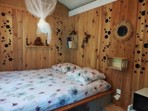a bedroom with a bed in a room with wooden walls at Echappée sauvage in Masquières
