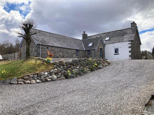 an old stone house with a stone wall at Jakels Rest in Lairg