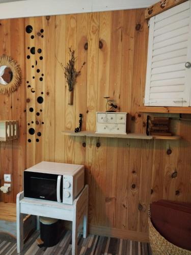 a microwave on a table in a room with wooden walls at Echappée sauvage in Masquières