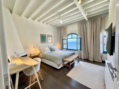 a bedroom with a bed and a desk and a window at Patmos Cliff House in Patmos