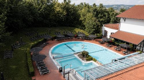 an overhead view of a swimming pool with chairs and umbrellas at DAS LUDWIG Sports Resort in Bad Griesbach