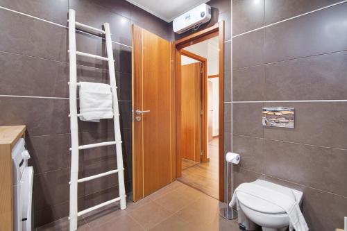 a bathroom with a toilet and a wooden door at Flor de Sol House in Tavira