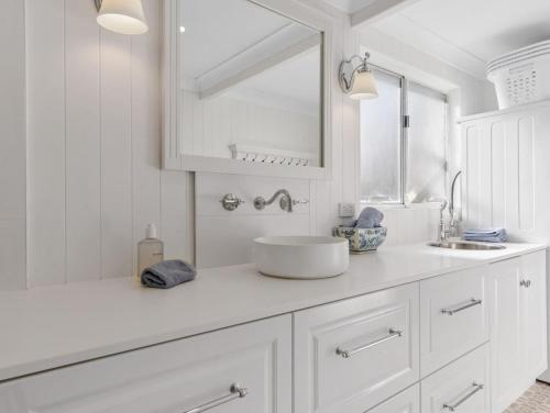 a white bathroom with a sink and a mirror at Elysian Shores in Long Beach