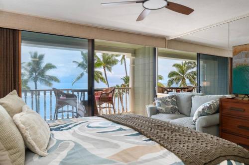 a bedroom with a bed and a couch and a balcony at Maui Beachfront Haven 433 in Lahaina