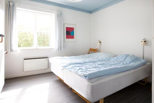 a white bedroom with a bed in a room with a window at Feriecentret Østersø Færgegård in Kalvehave