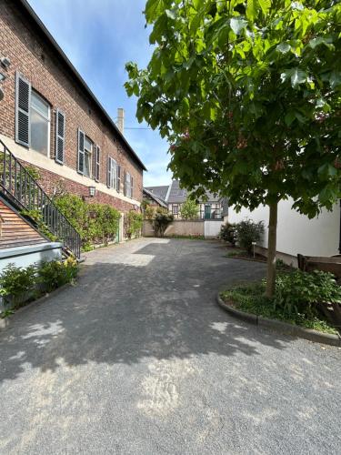 an empty driveway next to a brick building with a tree at Gästehaus Korf in Unkel