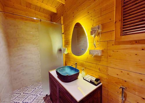 a bathroom with a blue sink and a wooden wall at Oyster Bay Beach Resort in Anjuna