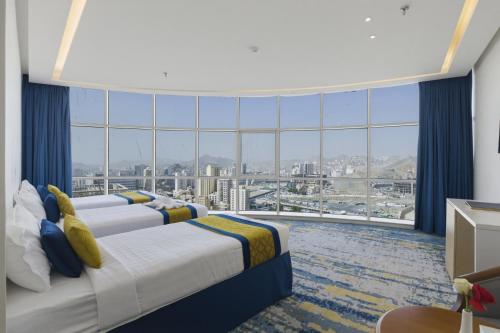 a hotel room with three beds and a large window at Taj Park Hotel in Mecca