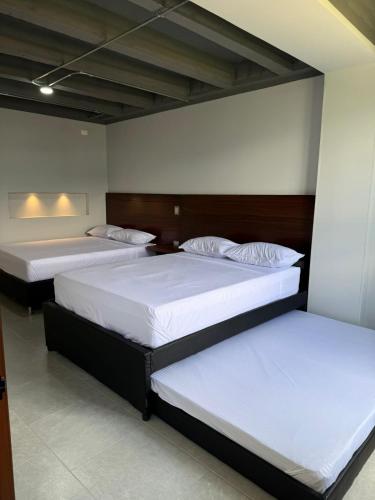 two beds in a room with white sheets at Hotel Provenza Suites in Ocaña