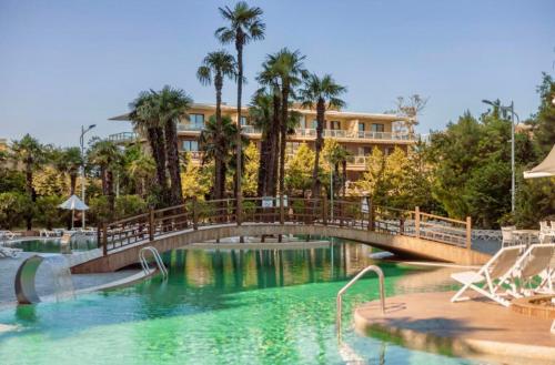 a bridge over a pool at a resort with palm trees at Dreamland Aparts in Chakvi