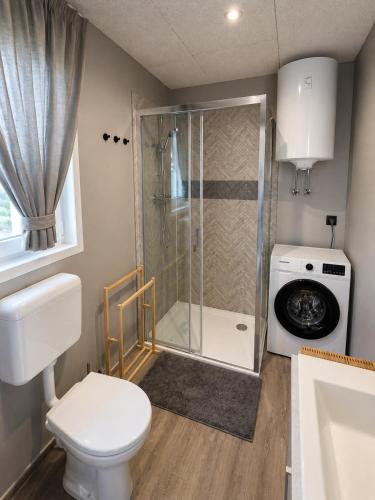 a bathroom with a shower and a toilet and a washing machine at Aurea Lux in Pakoštane