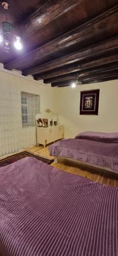 two beds in a room with purple sheets at Khinalig Shaiq Guest House in Xınalıq