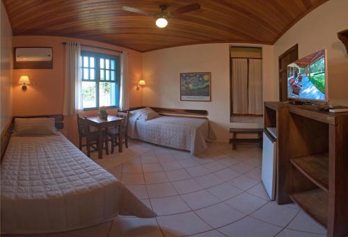 a bedroom with a bed and a tv in a room at Hotel Pousada da Lagoa in Garopaba