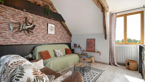 a living room with a couch and a brick wall at Gîte Les Légendes du Plessis in Iffendic