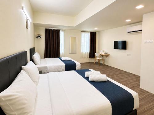 a hotel room with two beds and a television at Hotel Seri Warisan Melaka in Malacca