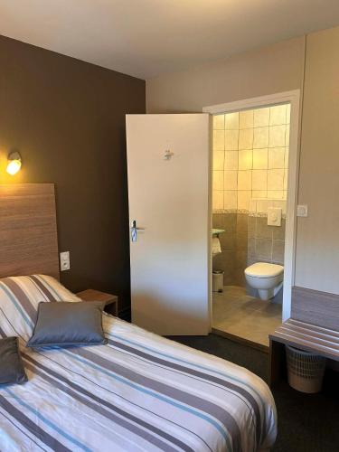 a bedroom with a bed and a bathroom with a toilet at Logis Hôtel Restaurant Les Cévennes in Saint-Cirgues-en-Montagne