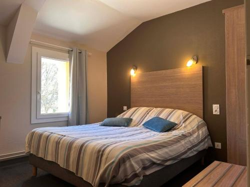 a bedroom with a bed with two blue pillows at Logis Hôtel Restaurant Les Cévennes in Saint-Cirgues-en-Montagne
