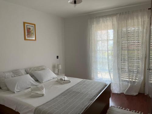 a white bedroom with a large bed and a window at Donna Seahouse in Jadranovo
