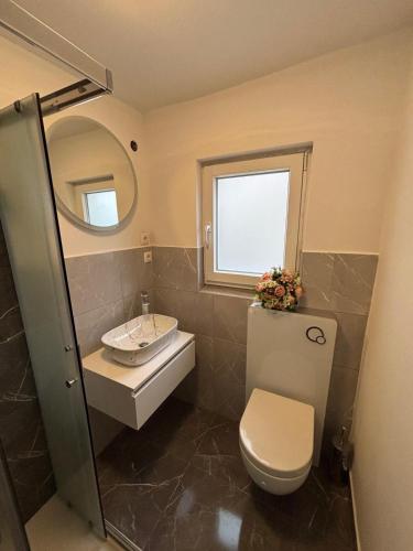 a bathroom with a sink and a toilet and a mirror at Donna Seahouse in Jadranovo