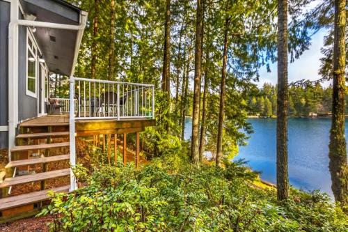 a house with a deck next to a lake at Lakefront retreat with view deck & private dock in Shelton