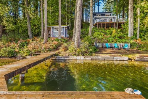 a house in the woods with a pond at Lakefront retreat with view deck & private dock in Shelton
