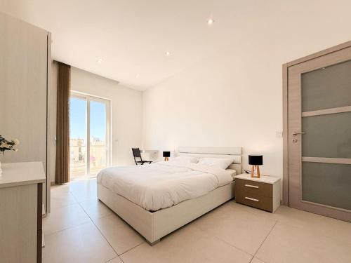 a white bedroom with a bed and a large window at St Julians - Spinola Space by DNA in St. Julianʼs