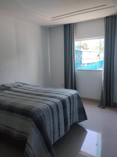 a bedroom with a bed with a striped blanket on it at Apê Boa Vista in Vila Velha