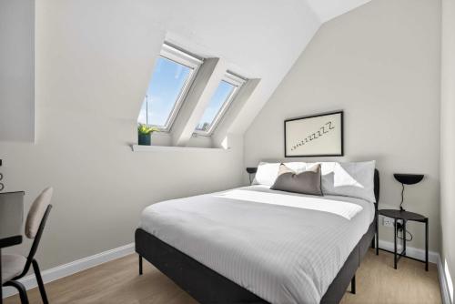 a white bedroom with a bed and two windows at Sanctuary Hotel - En Suite Rooms in Aberdeen