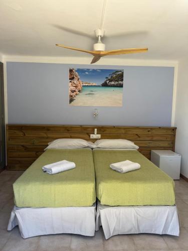 a bedroom with two beds and a ceiling fan at Hostal Playa in Cala Santanyi