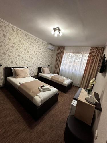 a hotel room with two beds and a chair at Pensiunea La Cuscrii in Arad