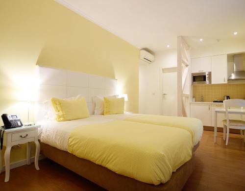 a bedroom with a large bed and a kitchen at Rossio Apartments in Lisbon