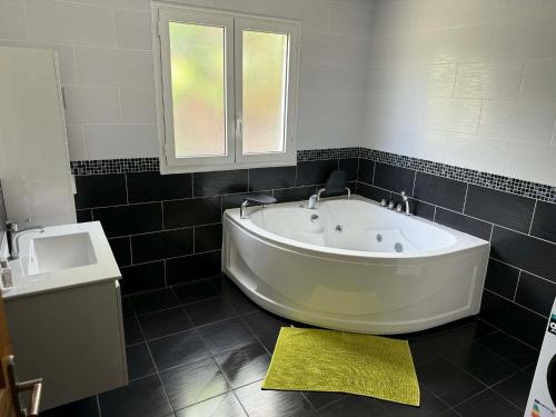 a bath tub in a bathroom with a yellow rug at Villa oasis des laves in Sainte-Rose