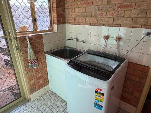 a small kitchen with a sink and a refrigerator at Good price Apartment self check-in in Geraldton