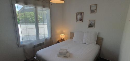 a bedroom with a white bed with a window at Maison familiale Montardon in Montardon