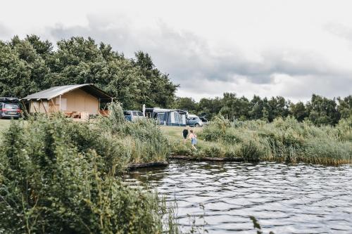 a young girl walking along a river with a tent at Vakantiepark de Kleine Wielen in Leeuwarden