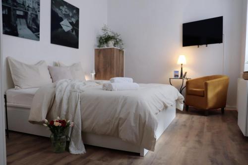 ein Schlafzimmer mit Bett, Stuhl und Fernseher in der Unterkunft Altmarktstudio1 in Cottbus