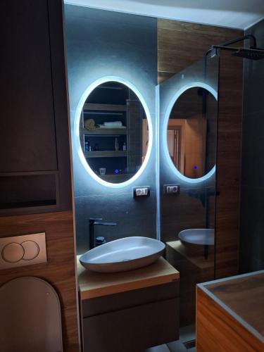a bathroom with a sink and two round mirrors at Golubac Bay Apartment in Golubac