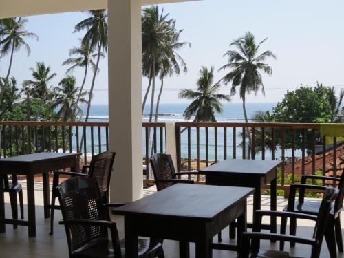 un patio con mesas y sillas y la playa en Sailors Mirissa, en Mirissa