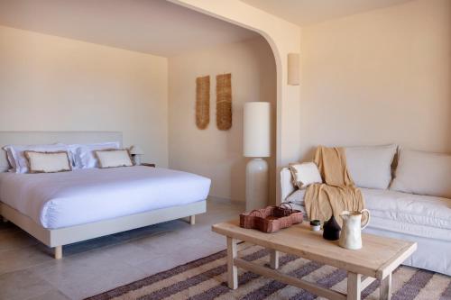 a bedroom with a bed and a couch at Les Paillers de Bodri - Vue mer et piscine - Adults Only in Corbara