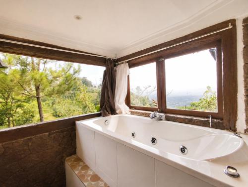 a bath tub in a bathroom with two windows at Dulang Resort & Resto in Bongkar 2