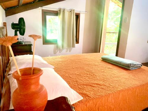 a bedroom with a bed and a vase with flowers in it at Pousada Jardim da Vida in Palmeiras