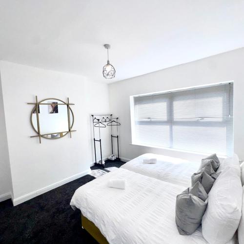 a white bedroom with a bed and a mirror at Bright Housing in Gateshead