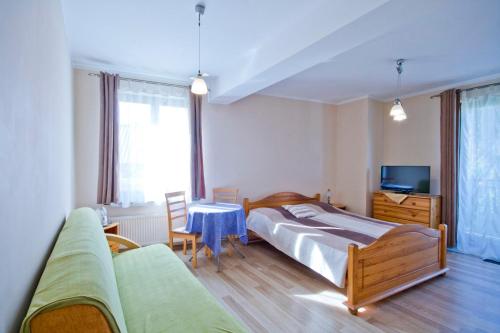 a bedroom with a bed and a couch and a table at Willa Ewa in Lądek-Zdrój
